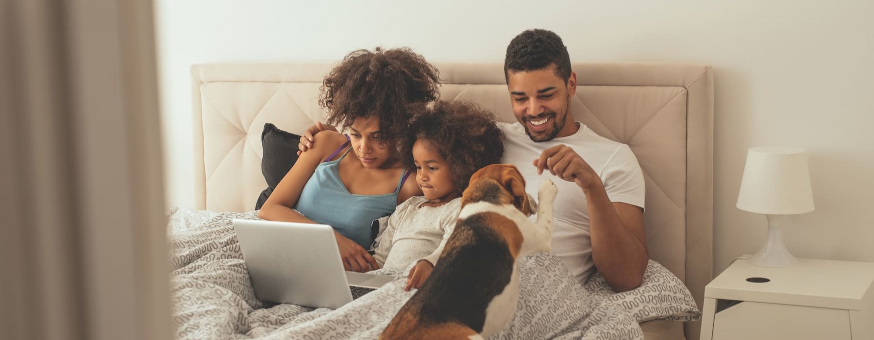 lifestyle image of a family in a bed with their dog